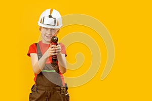 Little boy pretends to drill wall with drill against yellow isolated background. Boy teenager as builder worker. Copy space,