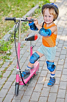 Little boy in protective helmet stands with pink