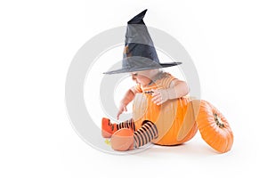 Little boy in a pumpkin in witch hat reaching for candy