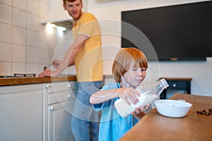 Little boy puring milk from the bottle to the plate