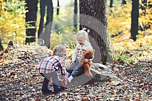 Little boy put shoes on girl feet. Brother help sister to put red boots. Helping hand concept. Children getting ready