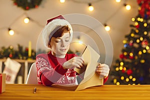 Little boy putting his letter and wish list in an envelope before sending them to Santa Claus