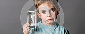 Little boy with questioning eyes holding a scary egg timer