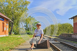 Little boy on a railway station, waiting for the train with vintage suitcase. Traveling, holiday and chilhood concept. Travel ins