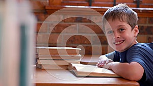 Little boy reading book in classroom