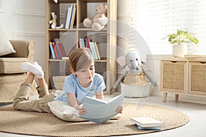 Little boy reading book on floor