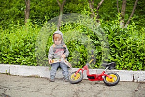 Little boy reading a book under big linden tree