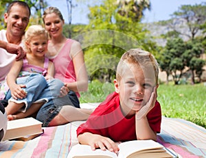 Little boy reading lying on the grass