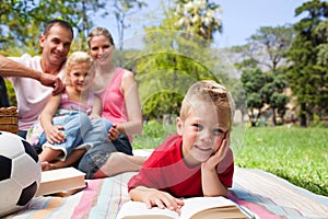 Little boy reading lying on the grass