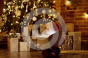 Little boy reading a magic book in decorated cozy living room