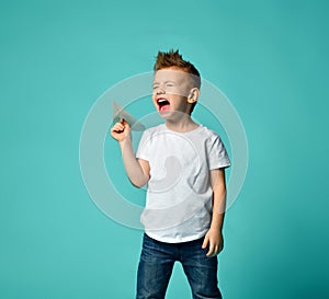 Little boy ready to launch a paper plane and shout with closed eyes. new step.