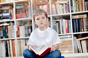 Little boy with red book in the library