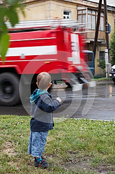 Little boy, red fire truck on road