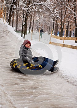 A little boy on a sled and goes down an ice slide