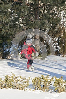 Little boy in red outfit playing happily over the snow