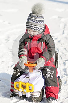 Little boy in red outfit playing happily over the snow