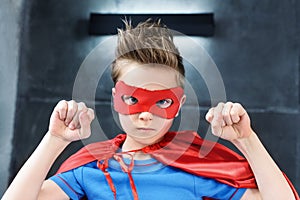 little boy in red superhero costume gesturing and looking