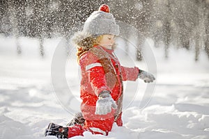 Little boy in red winter clothes having fun with snow. Active outdoors leisure with children in winter. Kid is playing in snow