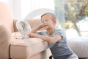 Little boy relaxing in front of fan at home