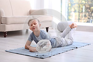 Little boy relaxing in front of fan at home.