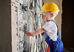 Little boy repairing electrical control panel at home.