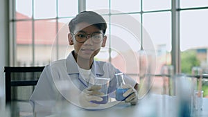 Little boy researches blue liquid in chemistry lesson at laboratory