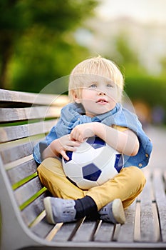 Little boy resting after playing a soccer/football game on summer day