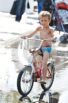 Little boy rides his bike among puddles