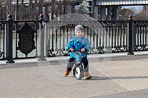 Little boy rides a runbike in the city.