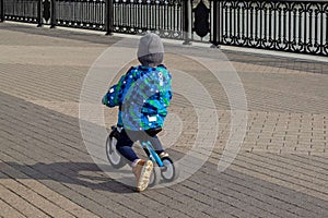Little boy riding a balance bike on a city sidewalk/