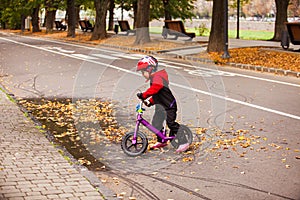 Little boy riding a balance bike near puddle