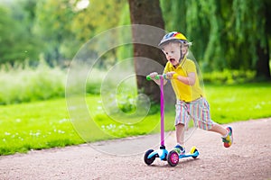 Little boy riding a colorful scooter