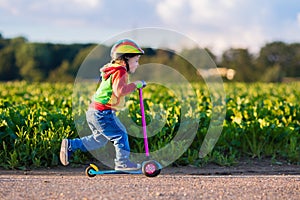 Little boy riding a colorful scooter