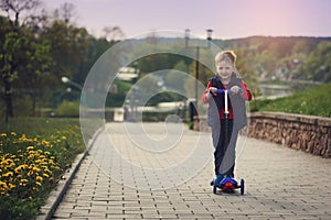 Little boy riding and his scooter bicycle in summer, outdoors