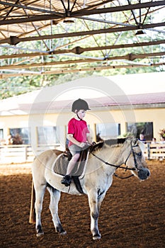 A little boy riding a horse. First lessons of horseback riding