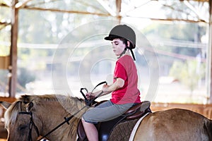 A little boy riding a horse. First lessons of horseback riding