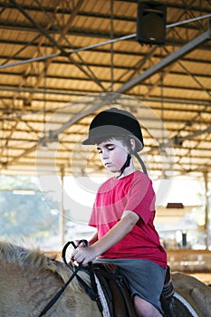 A little boy riding a horse. First lessons of horseback riding