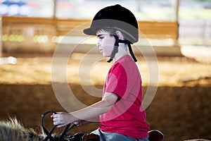 A little boy riding a horse. First lessons of horseback riding