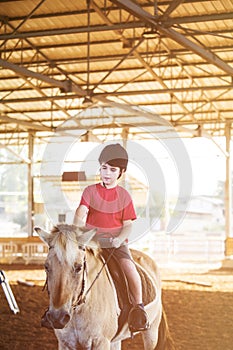 A little boy riding a horse. First lessons of horseback riding