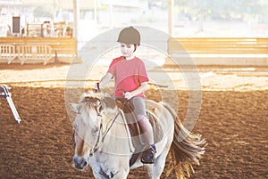 A little boy riding a horse. First lessons of horseback riding