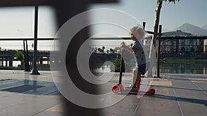 Little boy riding a kick scooter at the park