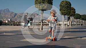 Little boy riding a kick scooter at the park