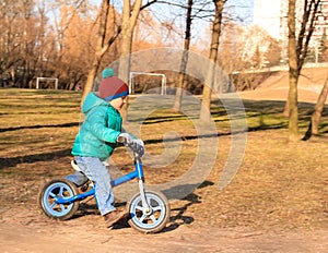 Little boy riding runbike in autumn park