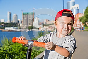 Little boy riding a scooter on the embankment