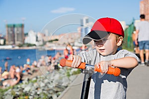 Little boy riding a scooter on embankment in Vladivostok