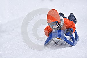 Little boy riding on snow slides in winter time