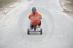 The little boy is riding a tricycle