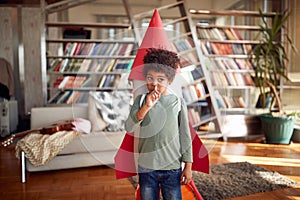 A little boy with a rocket toy on his back digs his nose while playing at home. Home, game, childhood