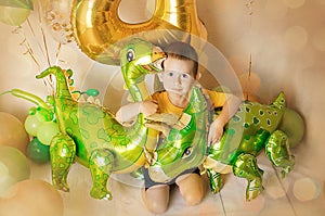 Little boy in room decorated for birthday party with baloons, large inflatable number 4, Dinosaur baloons
