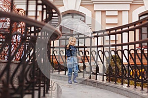 A little boy in rubber boots runs under an umbrella on a rainy day